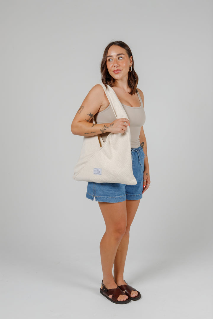 woman in jean shorts and a tank top wearing a Slouchy white Turkish cotton hobo shoulder sling bag on her shoulder against a plain grey background