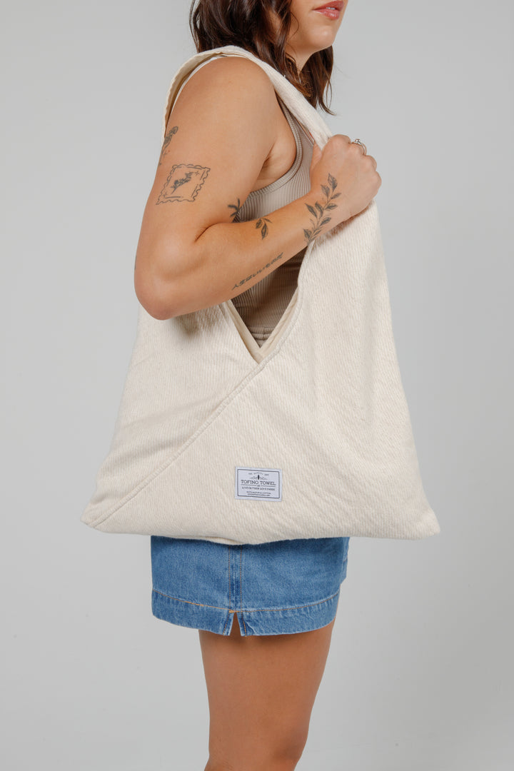 woman in jean shorts and a tank top wearing a Slouchy white Turkish cotton hobo shoulder sling bag on her shoulder against a plain grey background