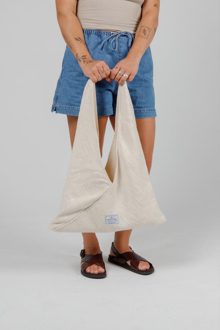 woman in jean shorts and a tank top holding a Slouchy white Turkish cotton hobo shoulder sling bag against a plain grey background
