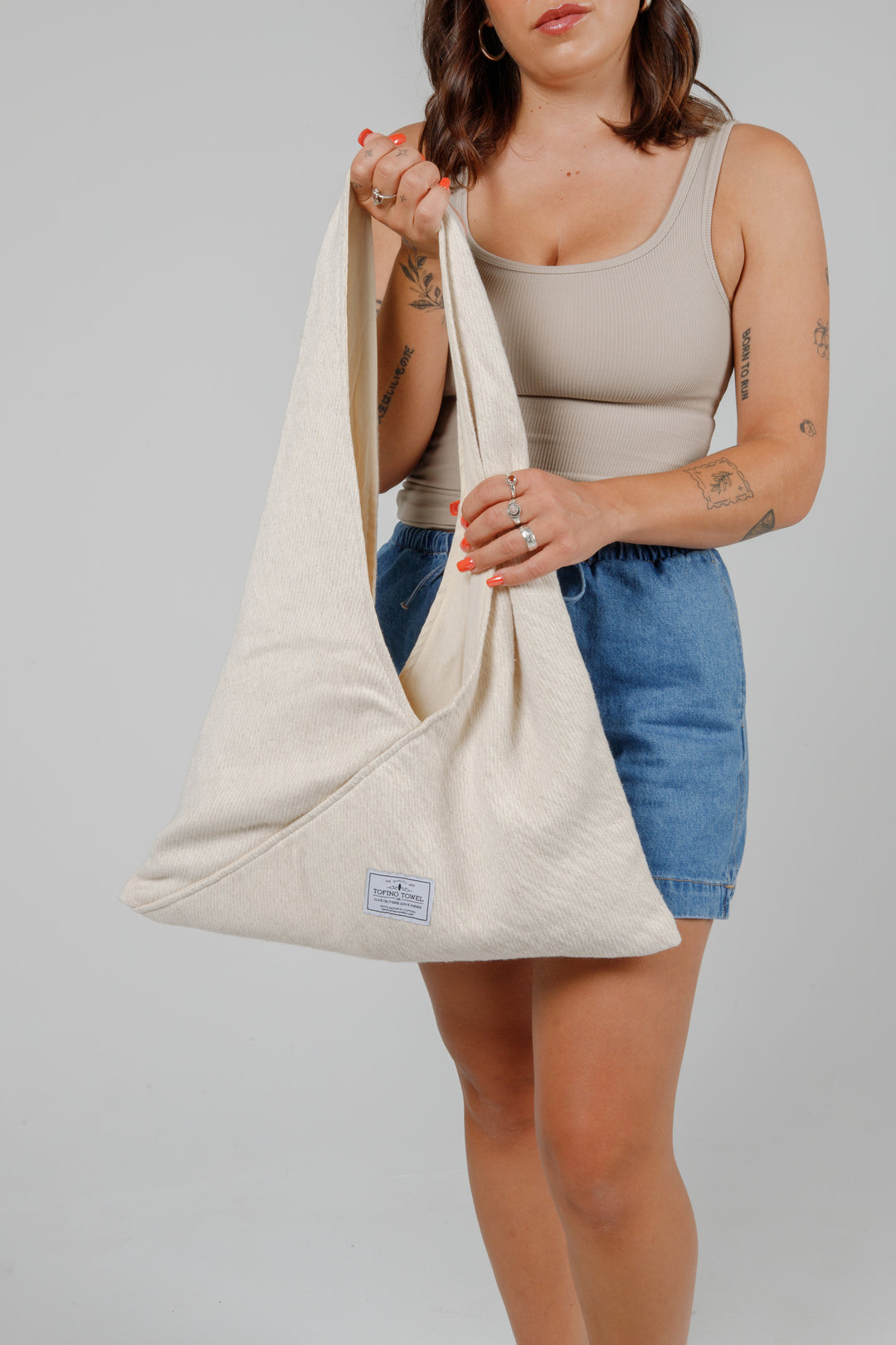 woman in jean shorts and a tank top holding a Slouchy white Turkish cotton hobo shoulder sling bag against a plain grey background