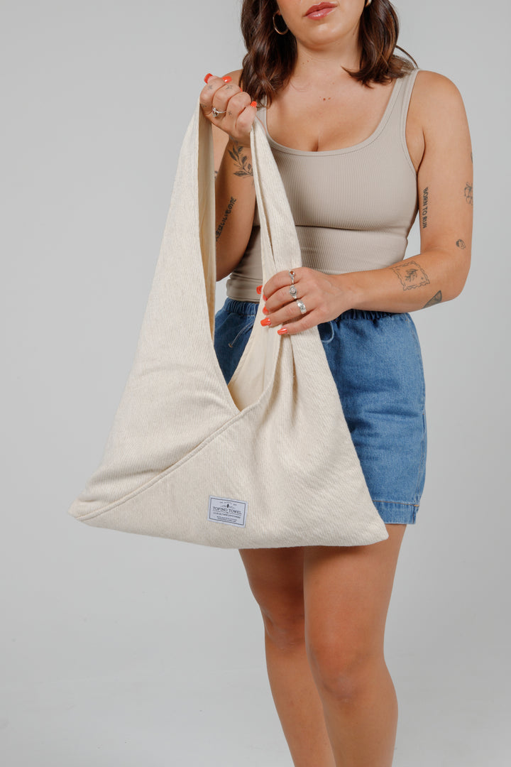 woman in jean shorts and a tank top holding a Slouchy white Turkish cotton hobo shoulder sling bag against a plain grey background