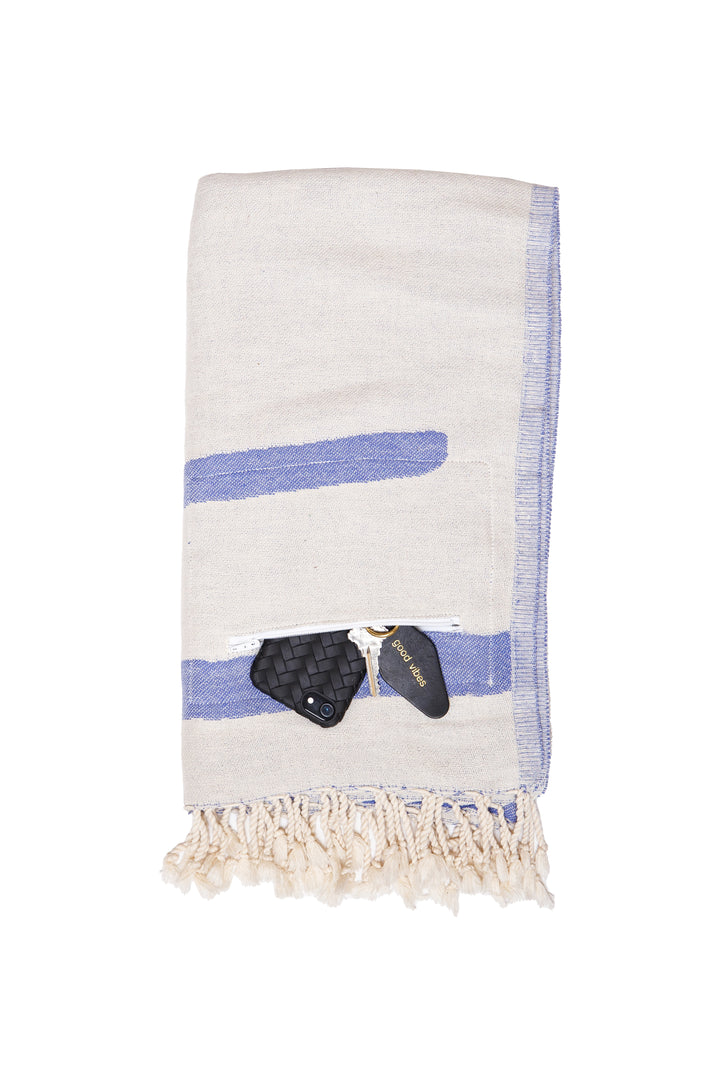 Turkish cotton towel with an abstract white and blue design. eyelash fringe and discreet zipper pocket folded on a white background #colour_blue