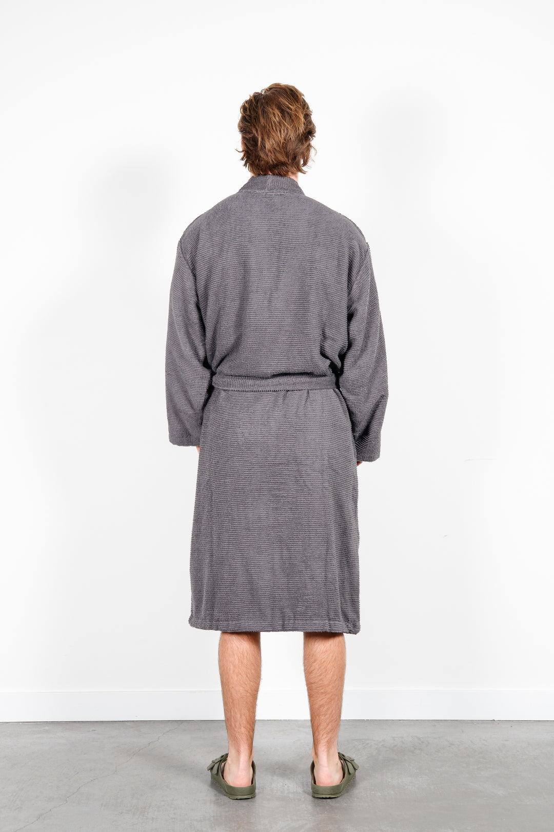 man standing backwards wearing mid length dark grey cotton terry relaxed fit spa robe #colour_charcoal