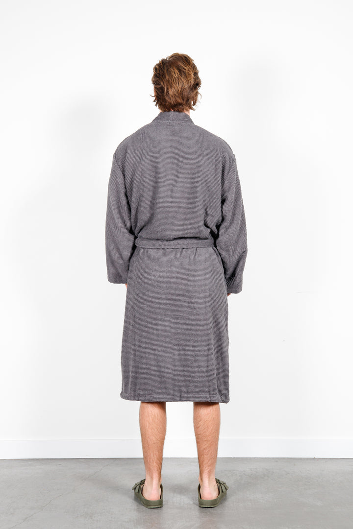 man standing backwards wearing mid length dark grey cotton terry relaxed fit spa robe #colour_charcoal