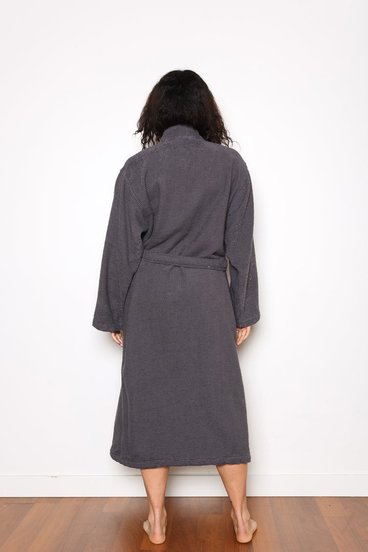woman standing backwards wearing mid length dark grey cotton terry relaxed fit spa robe #colour_charcoal