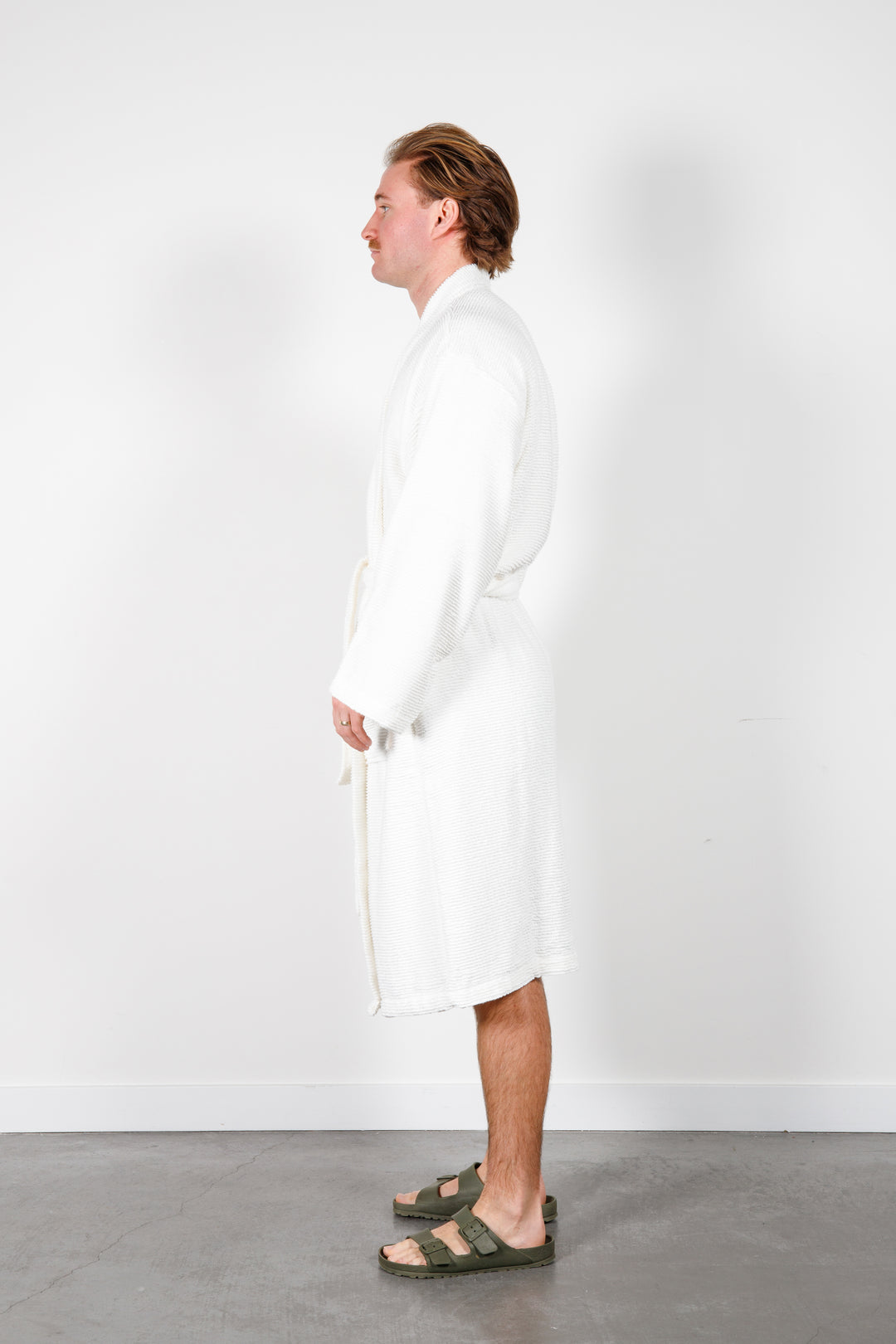 man wearing mid length white cotton terry relaxed fit spa robe #colour_off-white