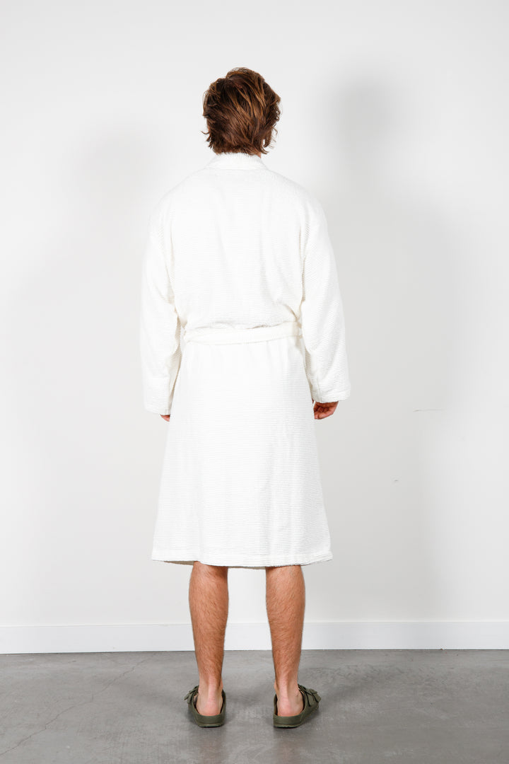 man standing backwards wearing mid length white cotton terry relaxed fit spa robe #colour_off-white