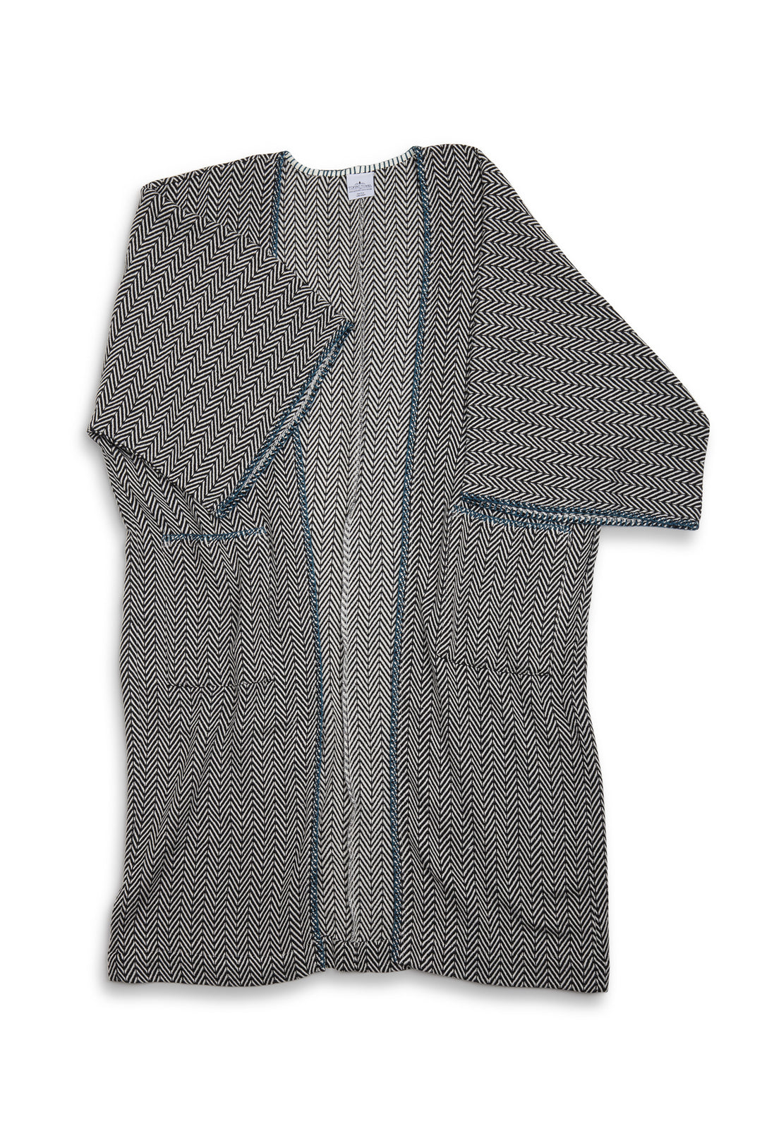 Long, herringbone patterned cardigan with blue whipstitch and pockets laid flat on a white background