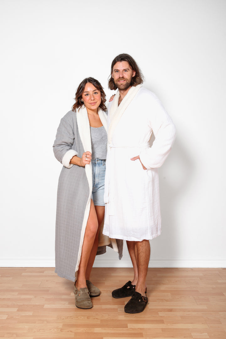 A man and woman wearing different colour long fleece lined muslin robes with pockets.#colour_grey