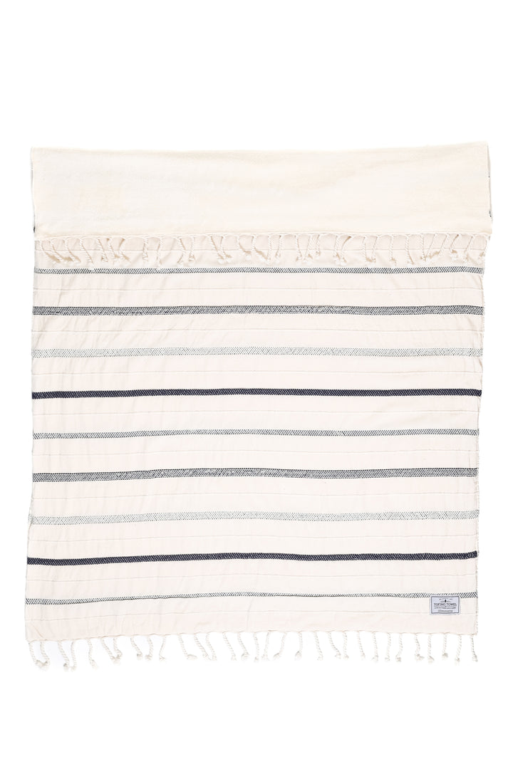 A fleece throw blanket with a striped pattern in navy and white, featuring rope-like stitch detailing and tassels at the edges.