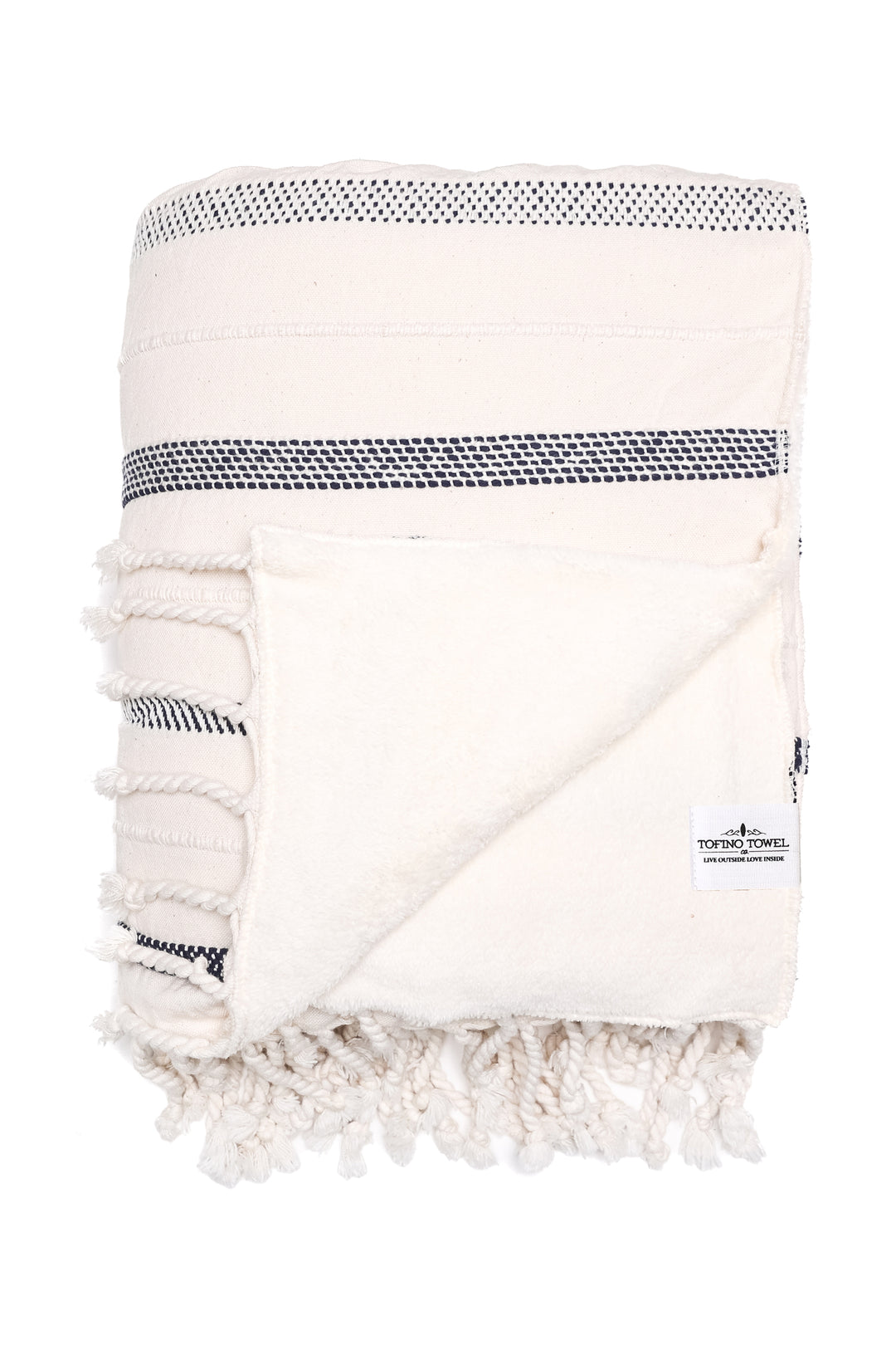 an off white fleece lined throw with different shades of navy stripes and tassels folded with one corner turned back on a white background
