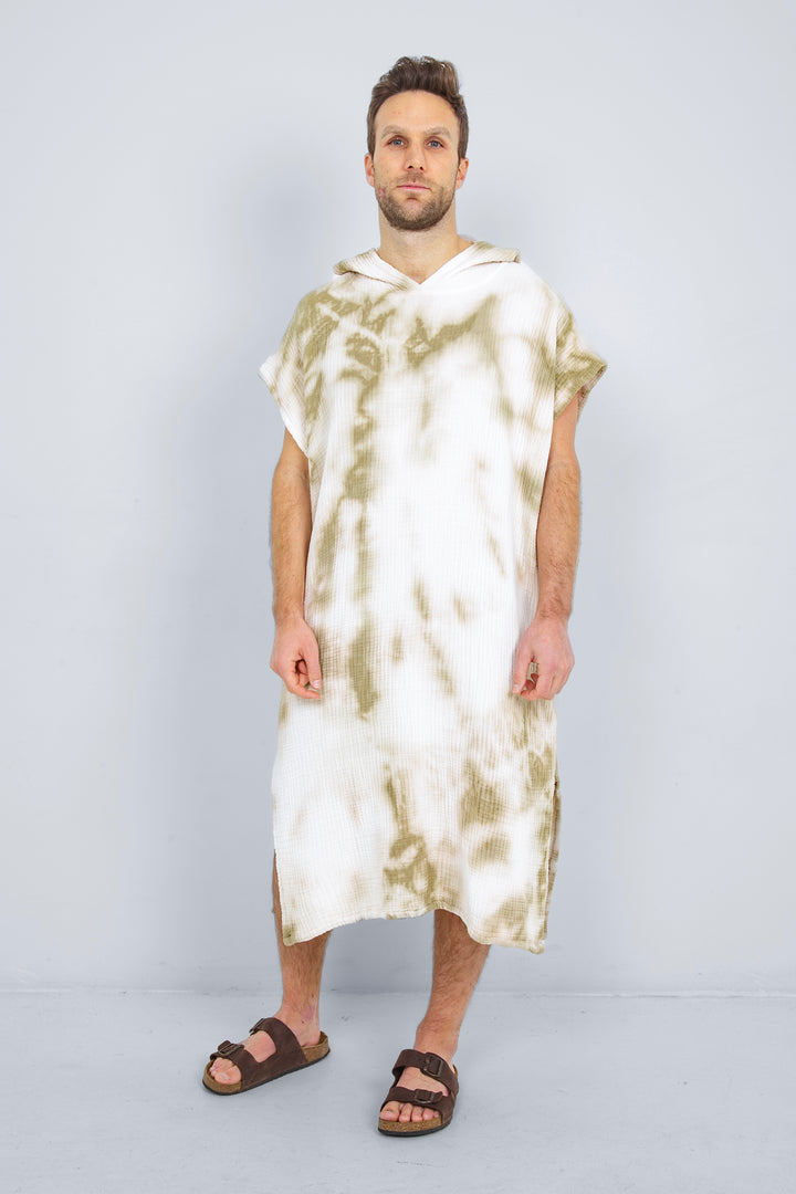A man standing wearing a white and beige khaki hooded, tie-dye muslin surf poncho with side slits  #colour_khaki-tie-dye