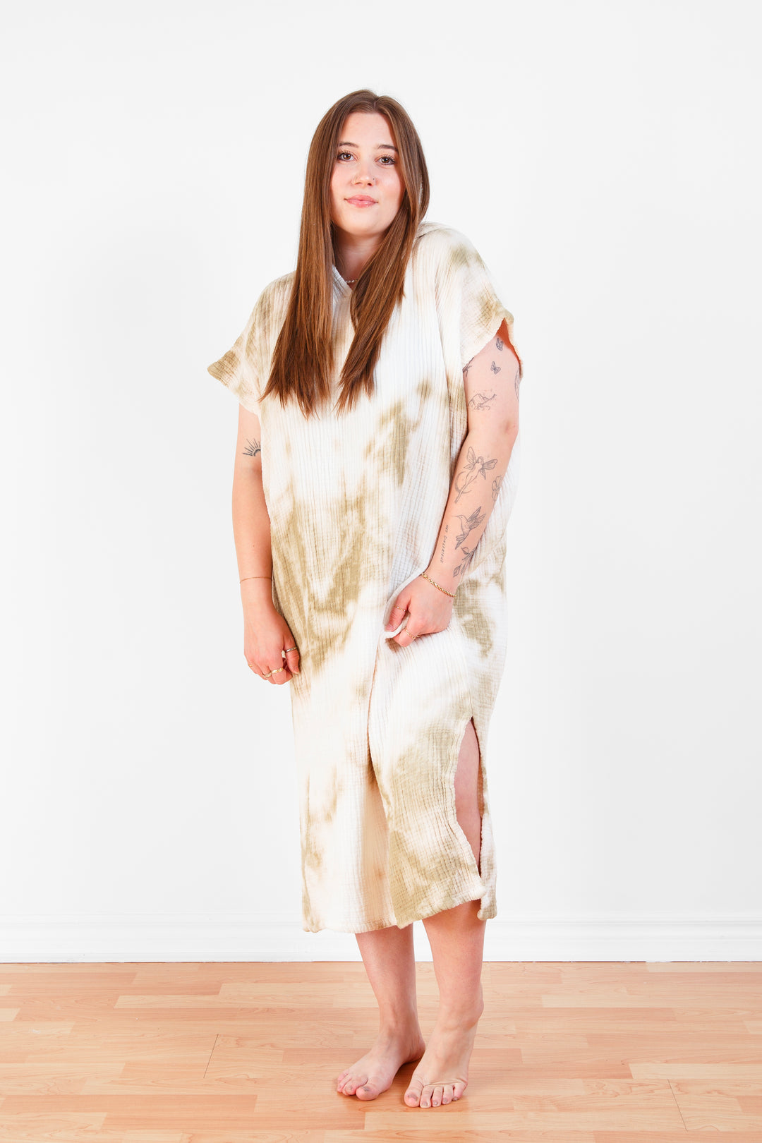 A woman standing wearing a white and beige khaki hooded, tie-dye muslin surf poncho with side slits  #colour_khaki-tie-dye