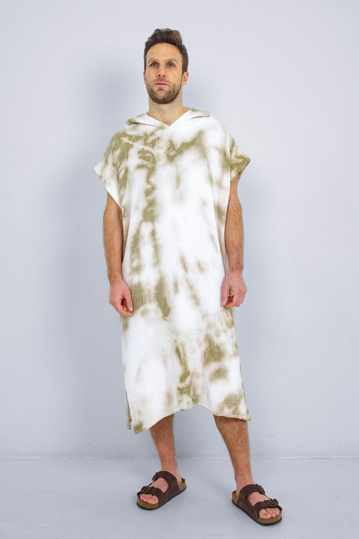 A man standing wearing a white and beige khaki hooded, tie-dye muslin surf poncho with side slits  #colour_khaki-tie-dye
