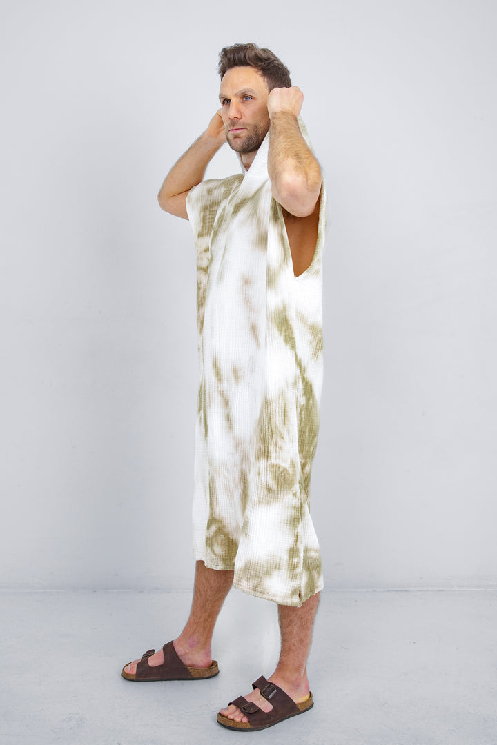 A man standing wearing a white and beige khaki hooded, tie-dye muslin surf poncho with side slits  #colour_khaki-tie-dye
