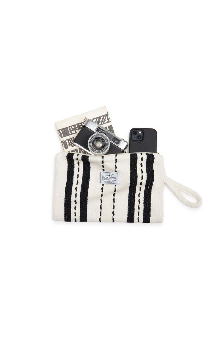 White zip up pouch with black stripes and a wrist handle containing a camera and phone on a white background