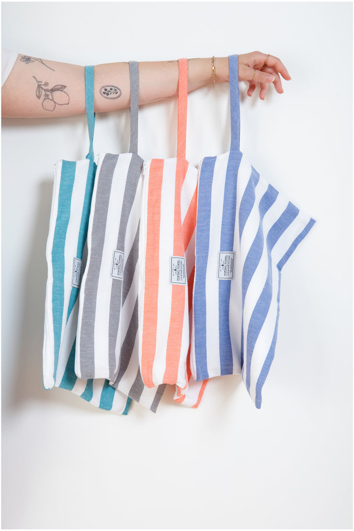 woman holding four different coloured large striped zipped pouches with wrist straps#colour_grey-stripes