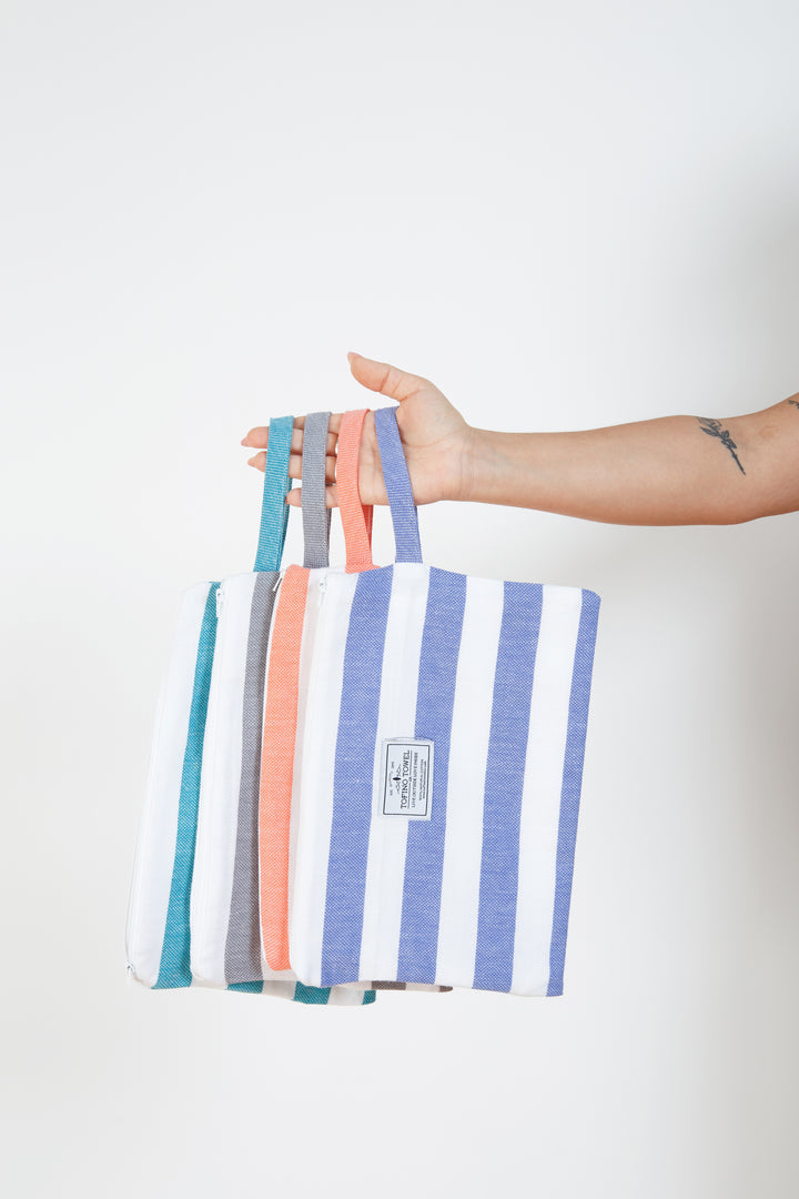 woman holding four different coloured striped zipped pouches with wrist straps#colour_grey-stripes