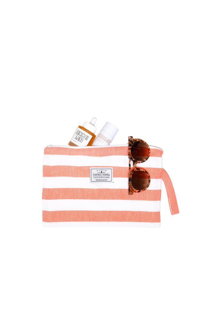 white and coral striped zip up pouch with wrist handle containing accessories on a white background #colour_coral-stripes