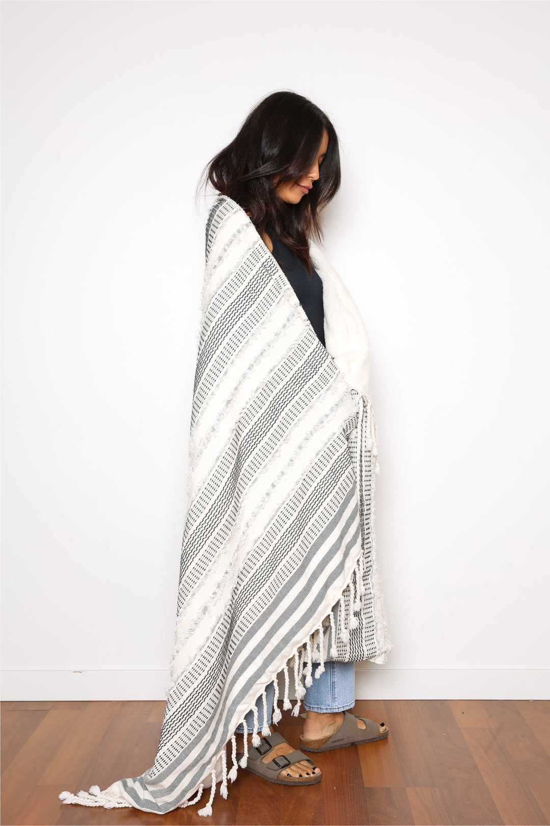 women wrapped in a cream and black fleece lined throw with textured stripes and tassels #colour_black-stripe
