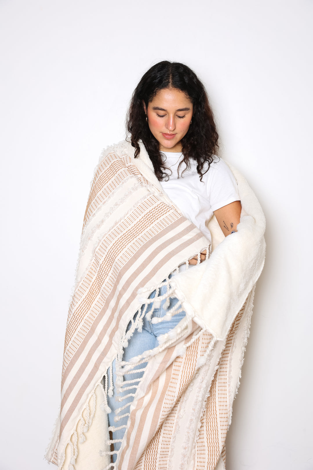 women wrapped in a cream and light brown fleece lined throw with textured stripes and tassels #colour_camel-stripe
