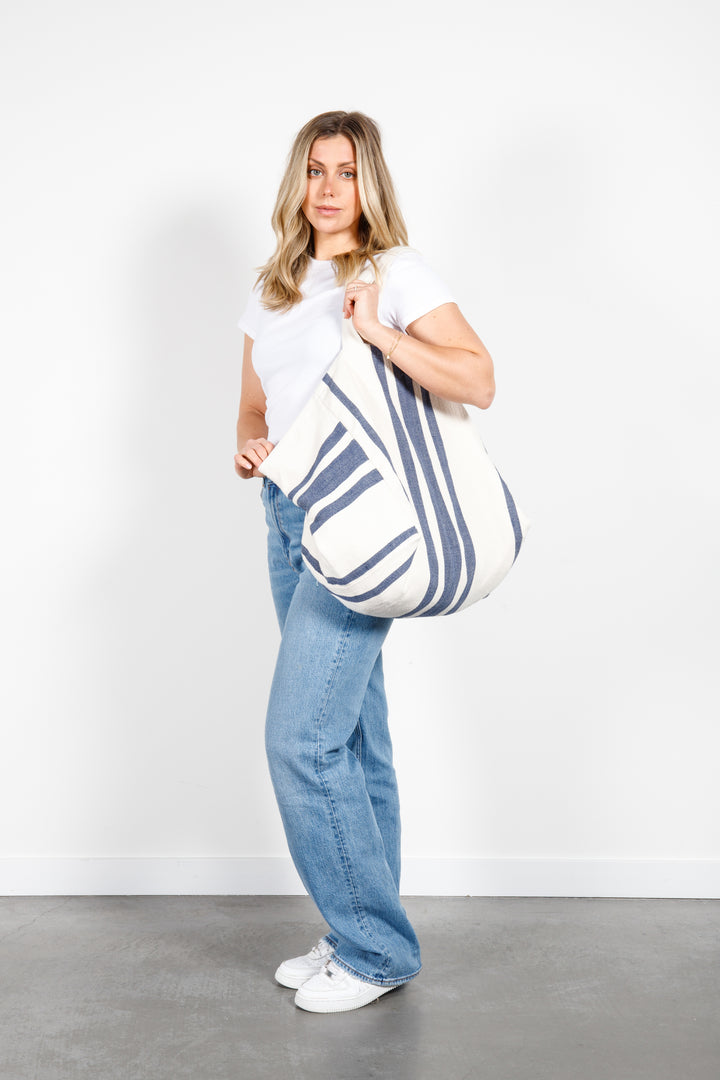 model in white tank top and blue jeans wearing oversized white and blue striped Turkish cotton tote bag on a white background #colour_navy