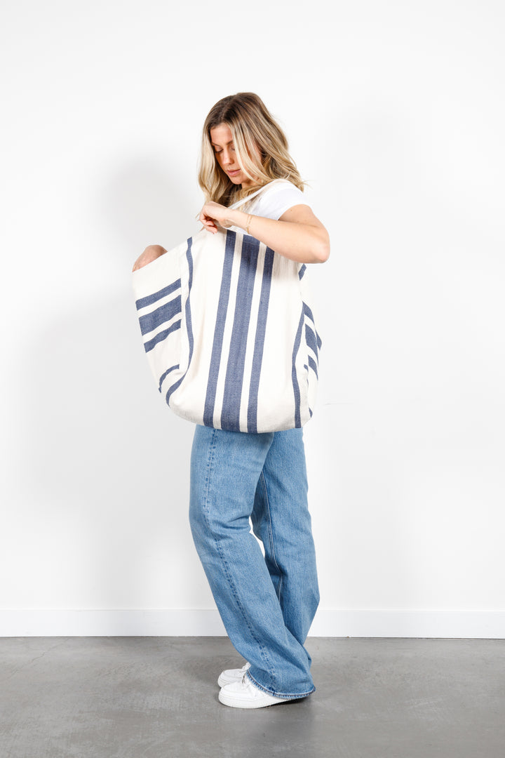 model in white tank top and blue jeans wearing oversized white and blue striped Turkish cotton tote bag on a white background #colour_navy