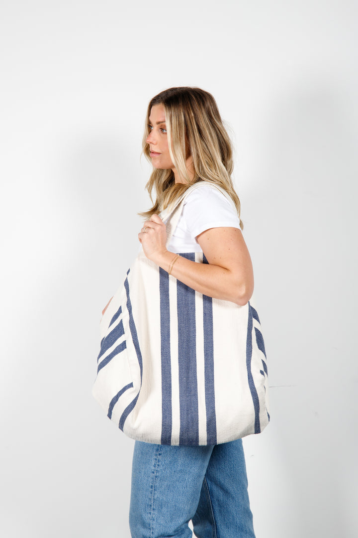 model in white tank top and blue jeans wearing oversized white and blue striped Turkish cotton tote bag on a white background #colour_navy