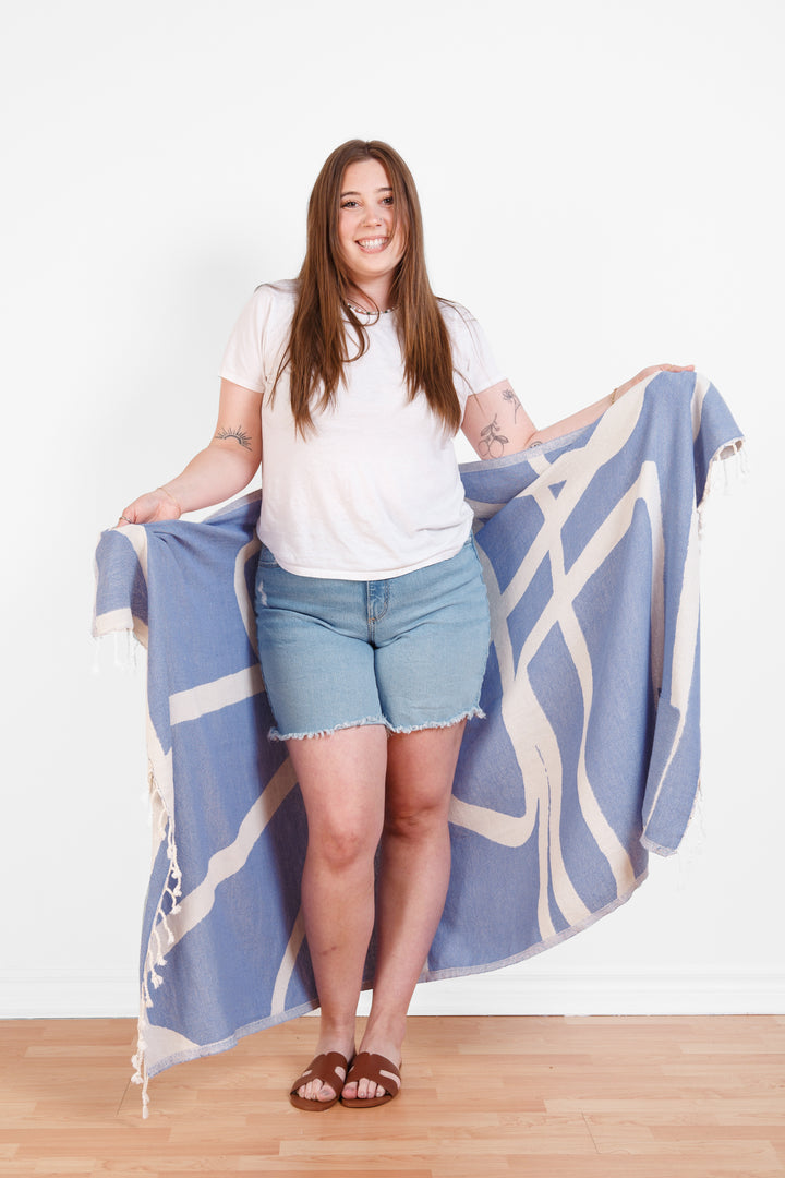 model wrapped in a Turkish cotton towel with an abstract white and blue design and eyelash fringe and on a white background #colour_blue
