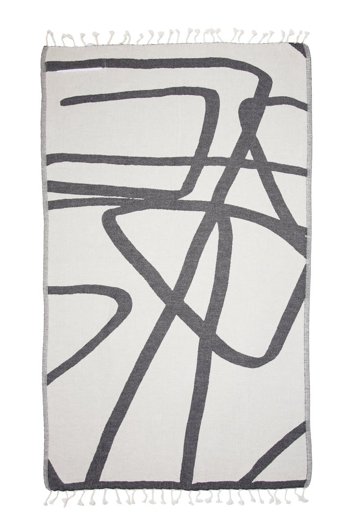 Turkish cotton towel with an abstract white and dark grey design and eyelash fringe laid flat on a white background #colour_granite