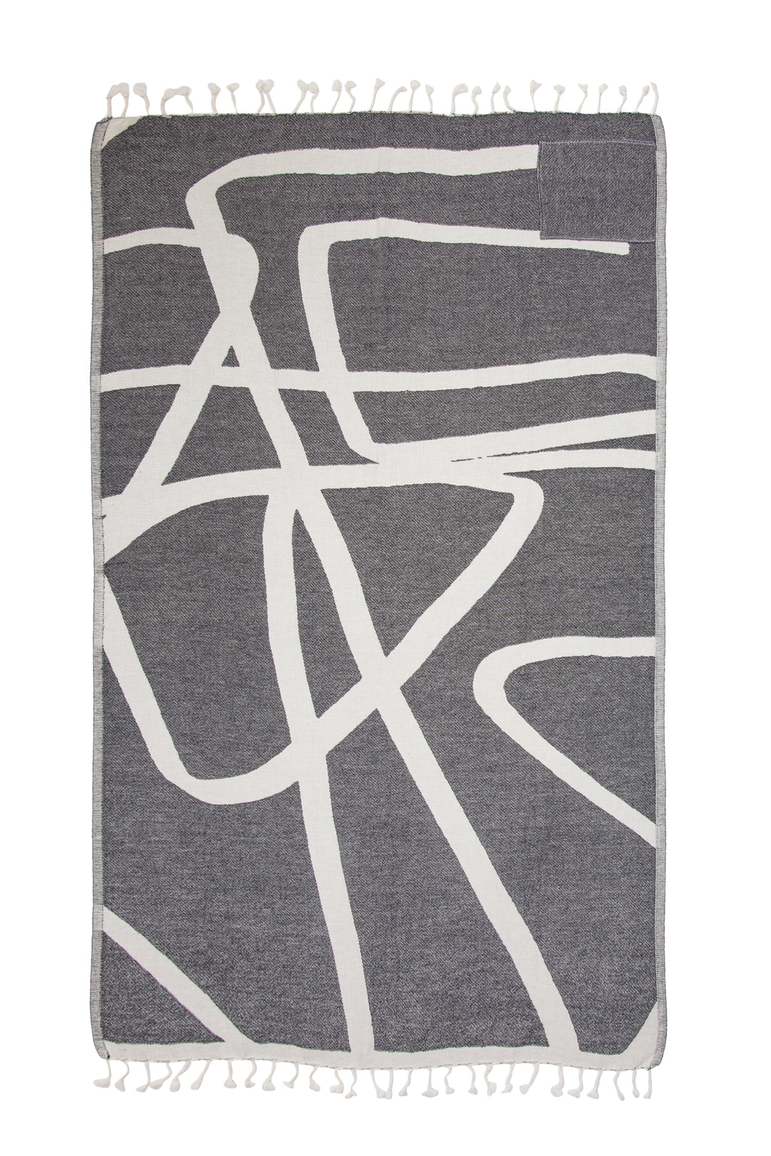 Turkish cotton towel with an abstract white and dark grey design, eyelash fringe and discreet zipper pocket laid flat on a white background #colour_granite