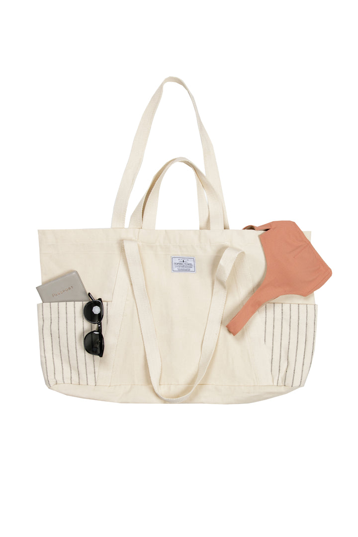 Large off white Turkish cotton canvas tote bag with exterior pockets and handles with accessories on a white background