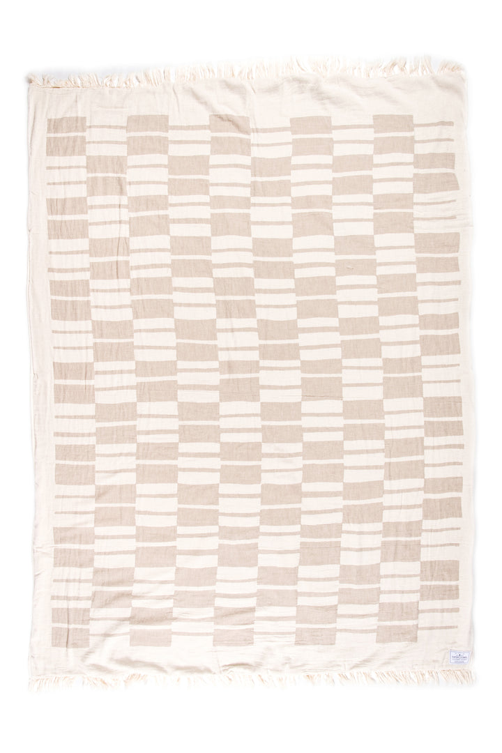 off white and beige fleece lined throw with modern checker board pattern and eyelash fringe laid flat on a white background  #colour_beige