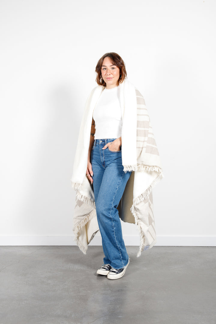 woman wrapped in an off white and beige fleece lined throw with modern checker board pattern and eyelash fringe   #colour_beige