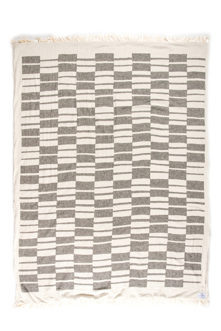 off white and dark grey fleece lined throw with modern checker board pattern and eyelash fringe laid flat on a white background #colour_granite