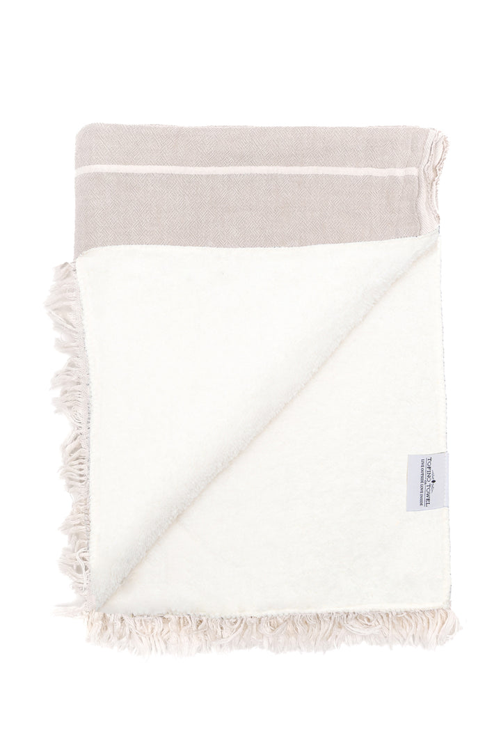 beige and off white fleece lined throw folded with one corner flipped back on a white background #colour_beige