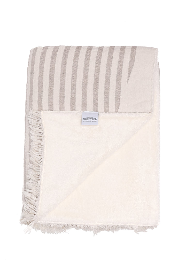 off white and baige fleece lined throw with eyelash fringe folded with one corner turned back on a white background #colour_beige