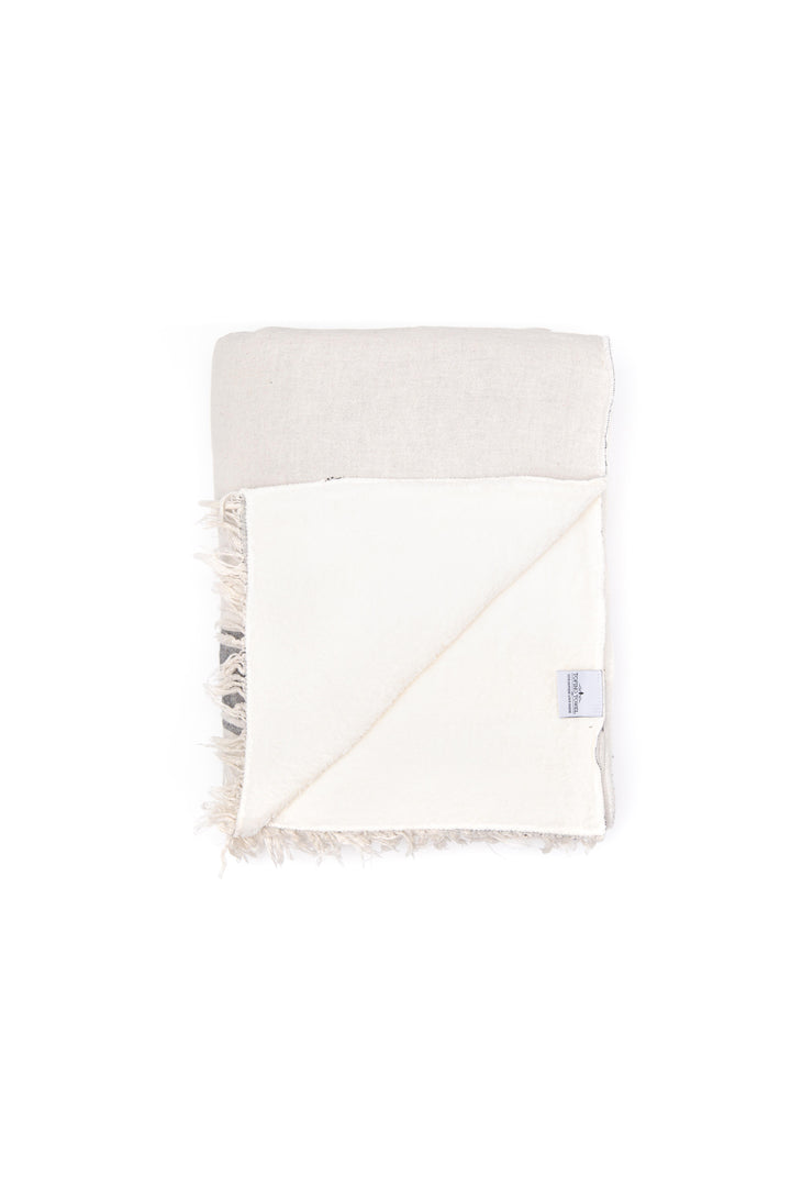 An off-white fleece-lined Turkish throw with eyelash fringe, and simple stylized grey stripes folded and displayed on a white background #colour_whitecap