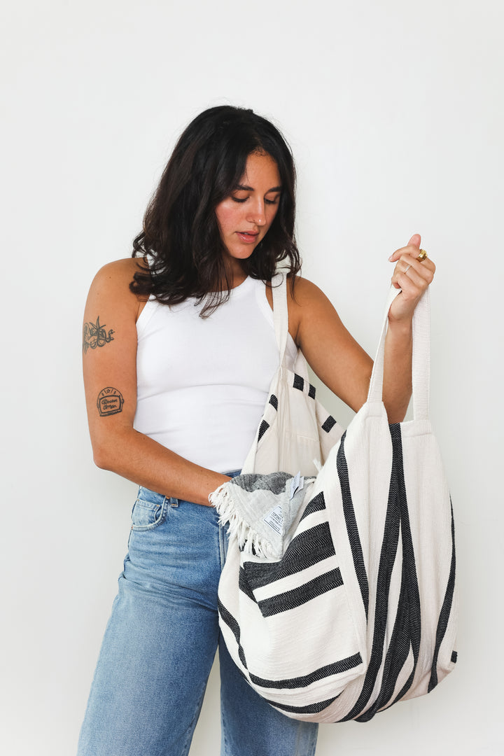 model in white tank top and blue jeans wearing oversized white and black striped Turkish cotton tote bag on a white background #colour_black