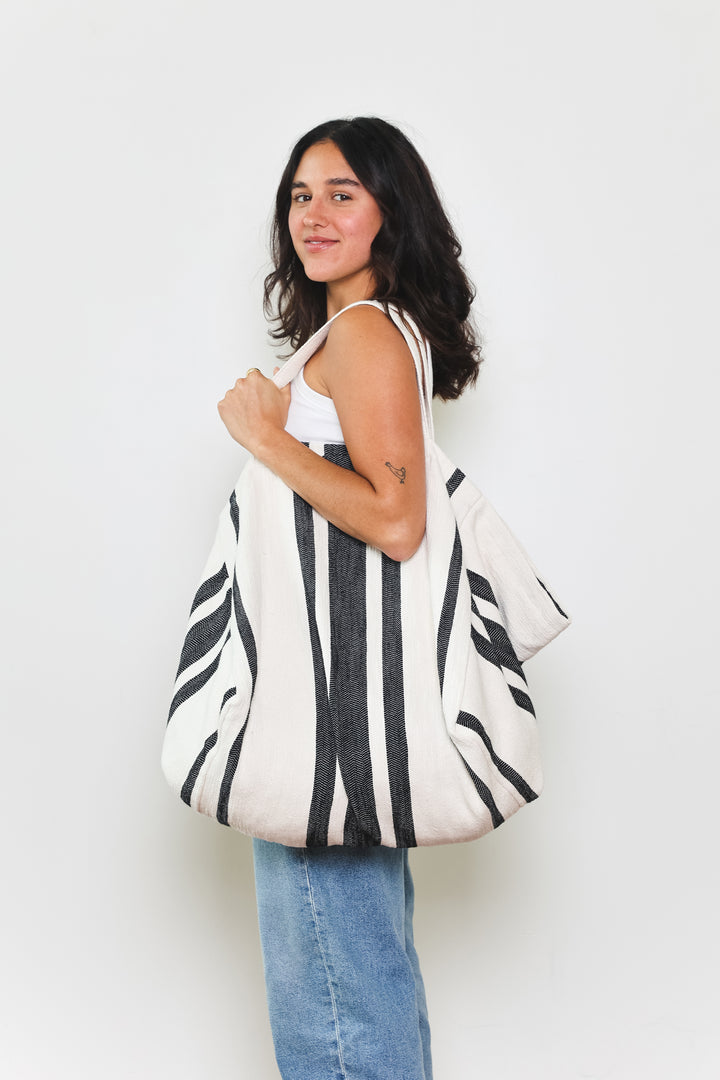 model in white tank top and blue jeans wearing oversized white and black striped Turkish cotton tote bag on a white background #colour_black
